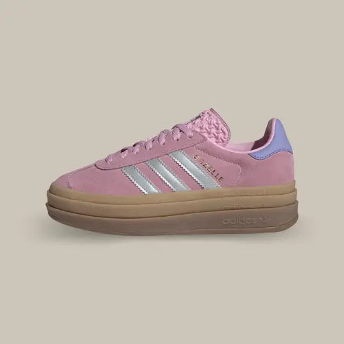 La Adidas Gazelle Bold True Pink Gum possède une base en suède rose bonbon avec les trois bandes emblématiques argentées. On retrouve un branding doré et un heel tab bleu clair qui vient contraster l'ensemble. La semelle surélevée en gomme de caoutchouc vient conclure ce magnifique modèle.