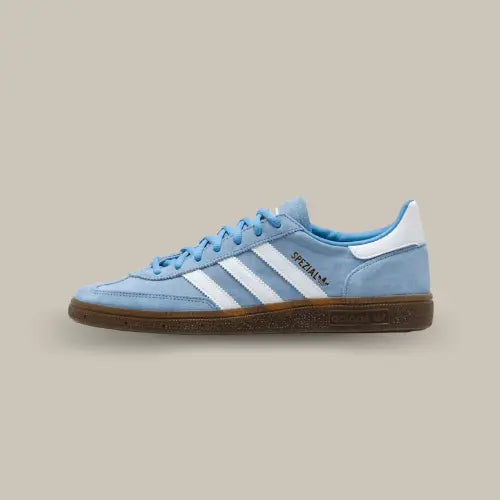 La Adidas Handball Spezial Light Blue de coté avec sa tige en suède bleu clair, ses trois bandes blanches assortis au talon et sa semelle en gomme.