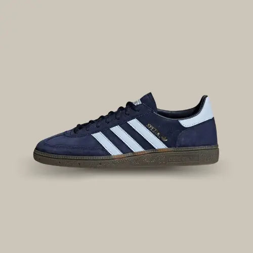 La Adidas Handball Spezial Navy Gum de coté avec sa tige en suède bleu profond, ses trois bandes bleu ciel et sa gomme en caoutchouc.