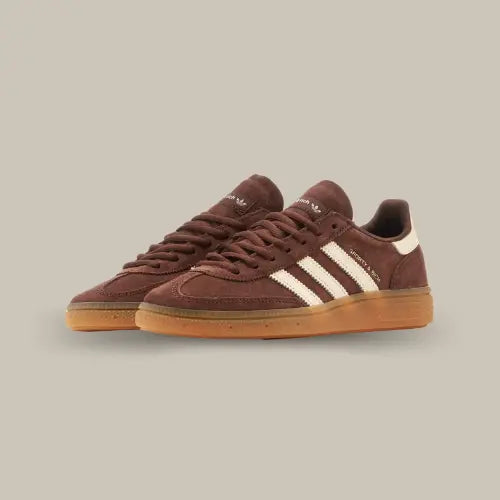 La Adidas Handball Spezial Sporty &amp; Rich Brown&nbsp;possède une base en&nbsp;daim marron&nbsp;avec les trois bandes blanches accordées au heel tab et au branding "Sporty &amp; Rich". La semelle en gomme de caoutchouc vient conclure cette maginfique paire de basket.