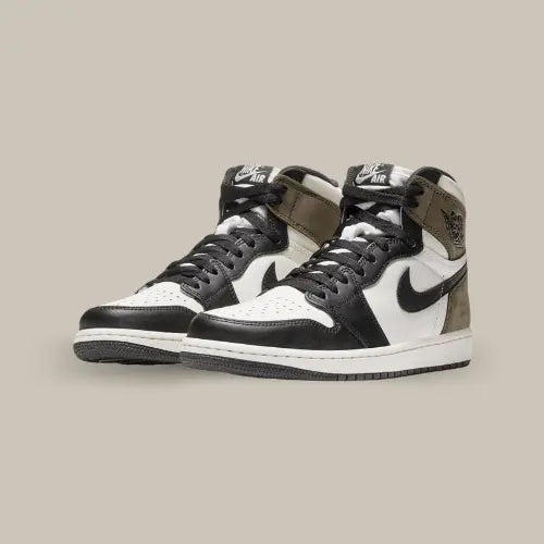 Cette Air Jordan 1 High Dark Mocha propose une tige en cuir blanc avec des empiècements noirs et des pièces en suède marron sur le talon. On retrouve un swoosh et les wings de couleur noir.