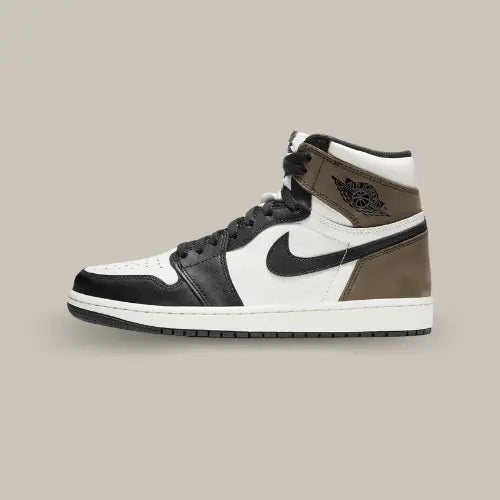 La Air Jordan 1 High Dark Mocha de coté avec sa base en cuir blanc et ses empiècement en cuir noir et suède marron au niveau du talon.