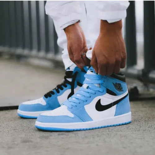 La Air Jordan 1 High University Blue portée avec un pantalon blanc.