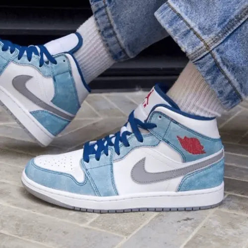 La Air Jordan 1 Mid French Blue Fire Red portée avec un jean clair.