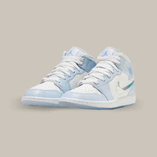 La Air Jordan 1 Mid Glitter Swoosh possède une base en cuir blanc avec des empiècements en cuir bleu ciel. On retrouve un swoosh brillant à effet miroir et le logo "Wings" bleu clair sur la talon accordé au logo Jumpman sur la languette.