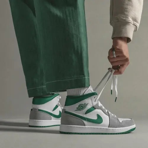 La Air Jordan 1 Mid Grey Green portée avec un pantalon vert.