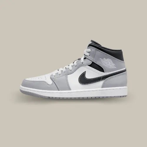 La Air Jordan 1 Mid Light Smoke Grey Anthracite vue de côté avec sa base en cuir blanc et gris et son swoosh noir.