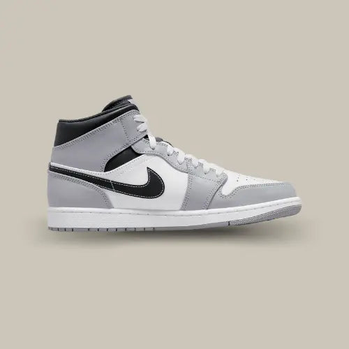 La Air Jordan 1 Mid Light Smoke Grey Anthracite vue de côté avec sa base en cuir blanc et gris et son swoosh noir.