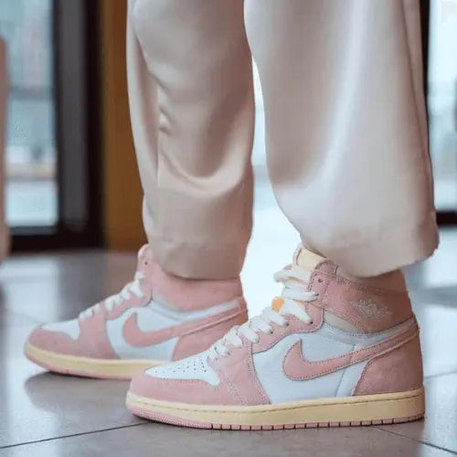 La Air Jordan 1 Retro High OG Washed Pink portée avec un pantalon blanc cassé.