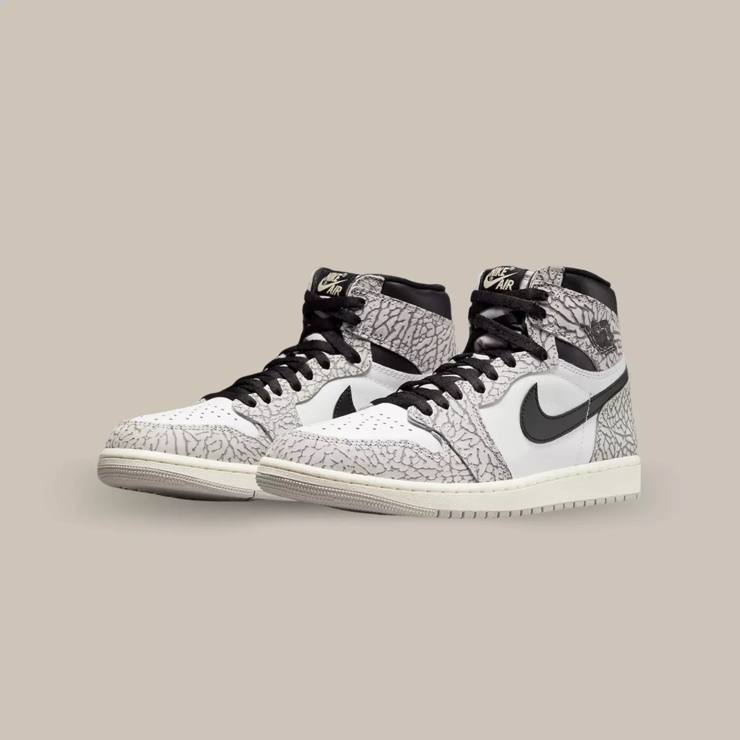 La Jordan 1 Retro High OG White Cement dévoile une base en cuir blanc accompagné d’un Swoosh en cuir noir accordé au col et au logo Wings sur la cheville. On distingue ensuite des empiècements en cuir habillé du mythique motif éléphant.