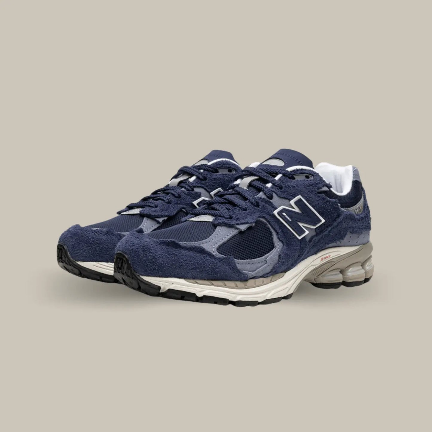 Cette New Balance 2002R Protection Pack Navy présente une base en mesh bleu marine, accompagnée de superpositions en suède bleu clair.