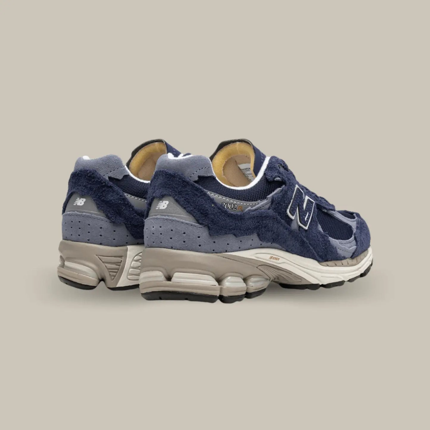 Cette New Balance 2002R Protection Pack Navy de dos avec une base en mesh bleu marine, accompagnée de superpositions en suède bleu clair.