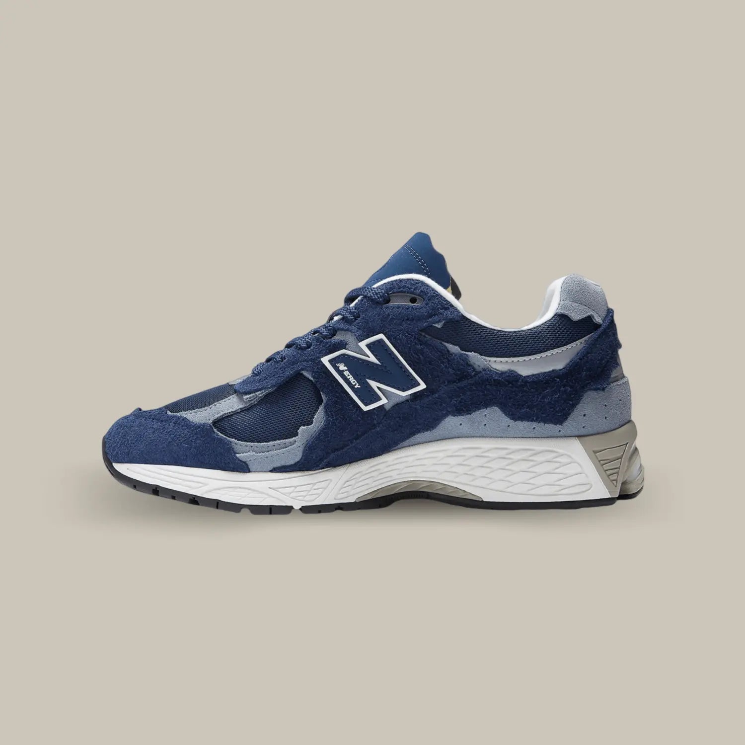 New Balance 2002R Protection Pack Navy de coté avec une base en mesh bleu marine, accompagnée de superpositions en suède bleu clair.