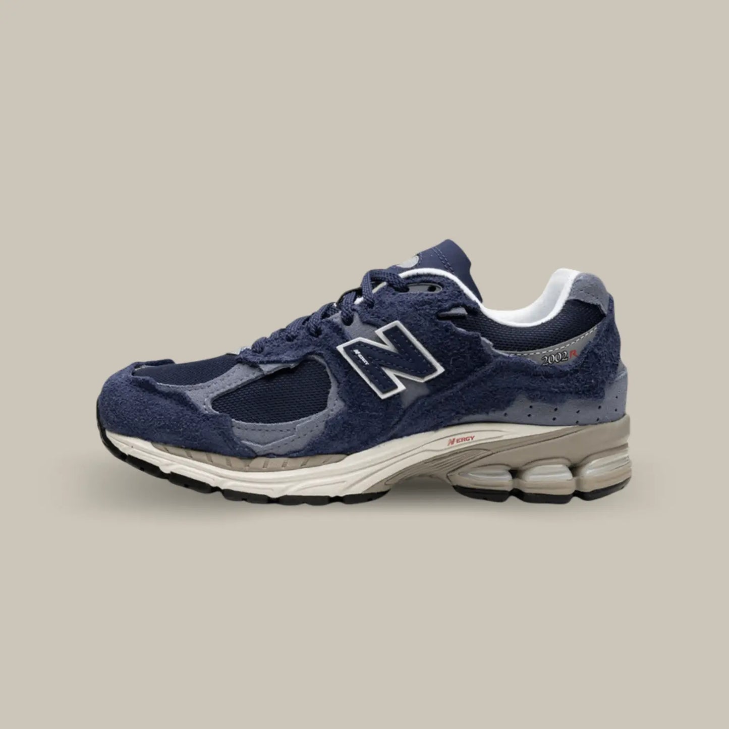 New Balance 2002R Protection Pack Navy de coté avec une base en mesh bleu marine, accompagnée de superpositions en suède bleu clair.