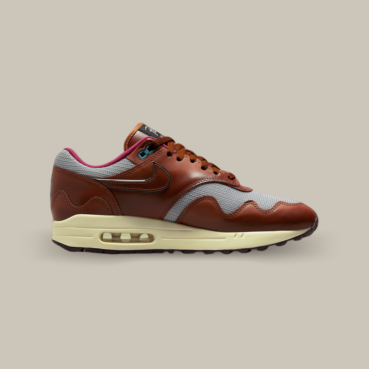 La Nike Air Max 1 Patta Dark Russet de coté avec sa structure mixte en mesh gris complétée par des superpositions en cuir marron sur tout le long de l’empeigne.