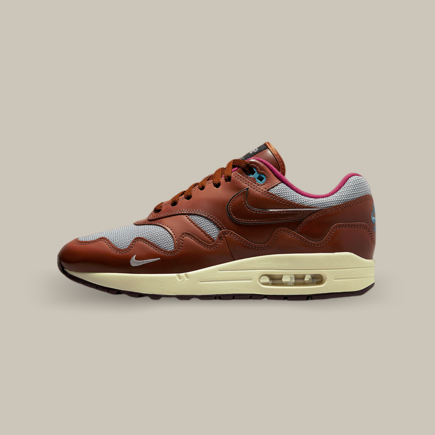 La Nike Air Max 1 Patta Dark Russet de coté avec sa structure mixte en mesh gris complétée par des superpositions en cuir marron sur tout le long de l’empeigne.