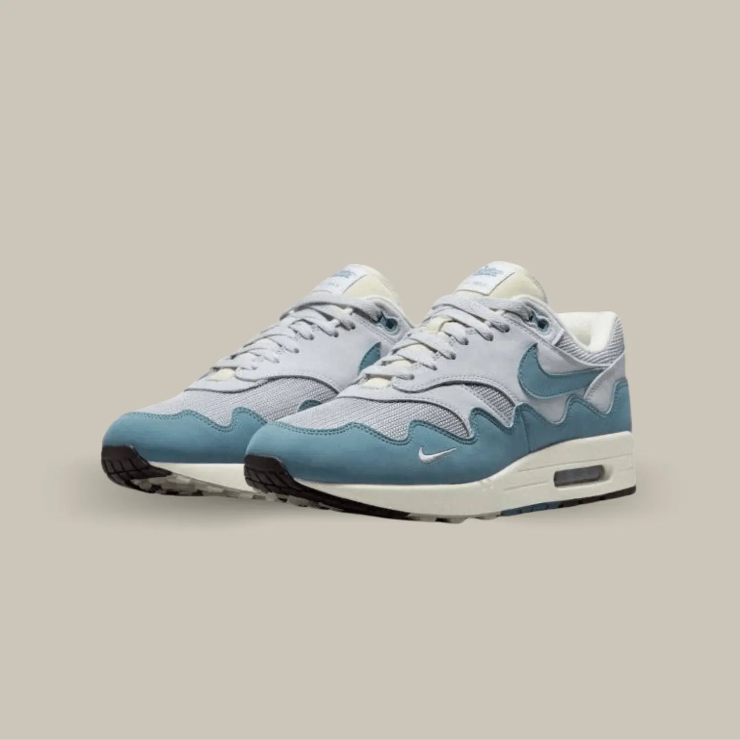 La Nike Air Max 1 Patta Noise Aqua possède une base une mesh et en cuir gris avec un empiècement ondulé en daim bleu. On retrouve un petit swoosh brodé sur le mudguard et le logo Patta sur la languette.