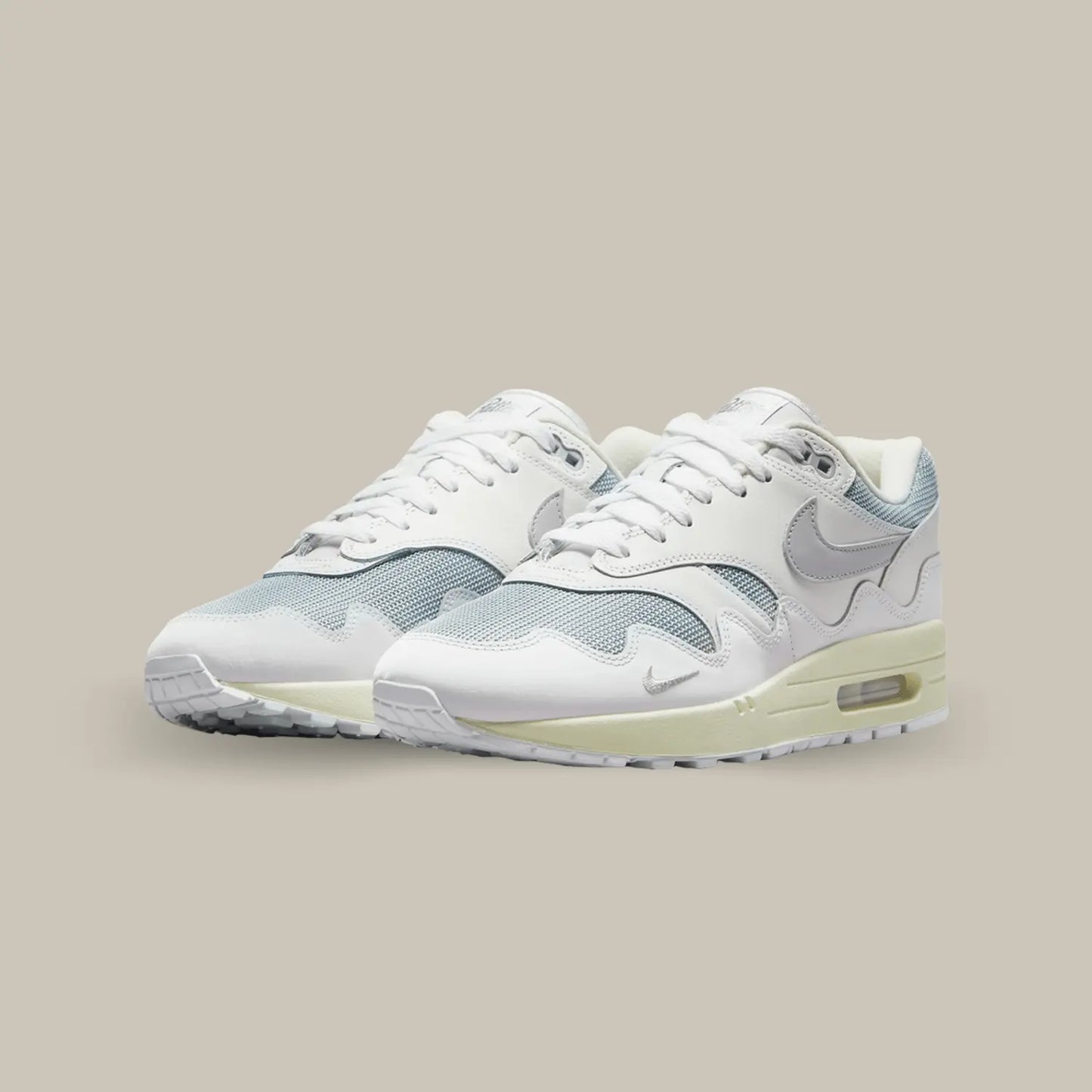 La Nike Air Max 1 Patta White Grey présente une base en mesh gris complétée par des superpositions de cuir blanc. Comme à son habitude avec Patta, on retrouve le mudguard ondulé en forme de vagues.