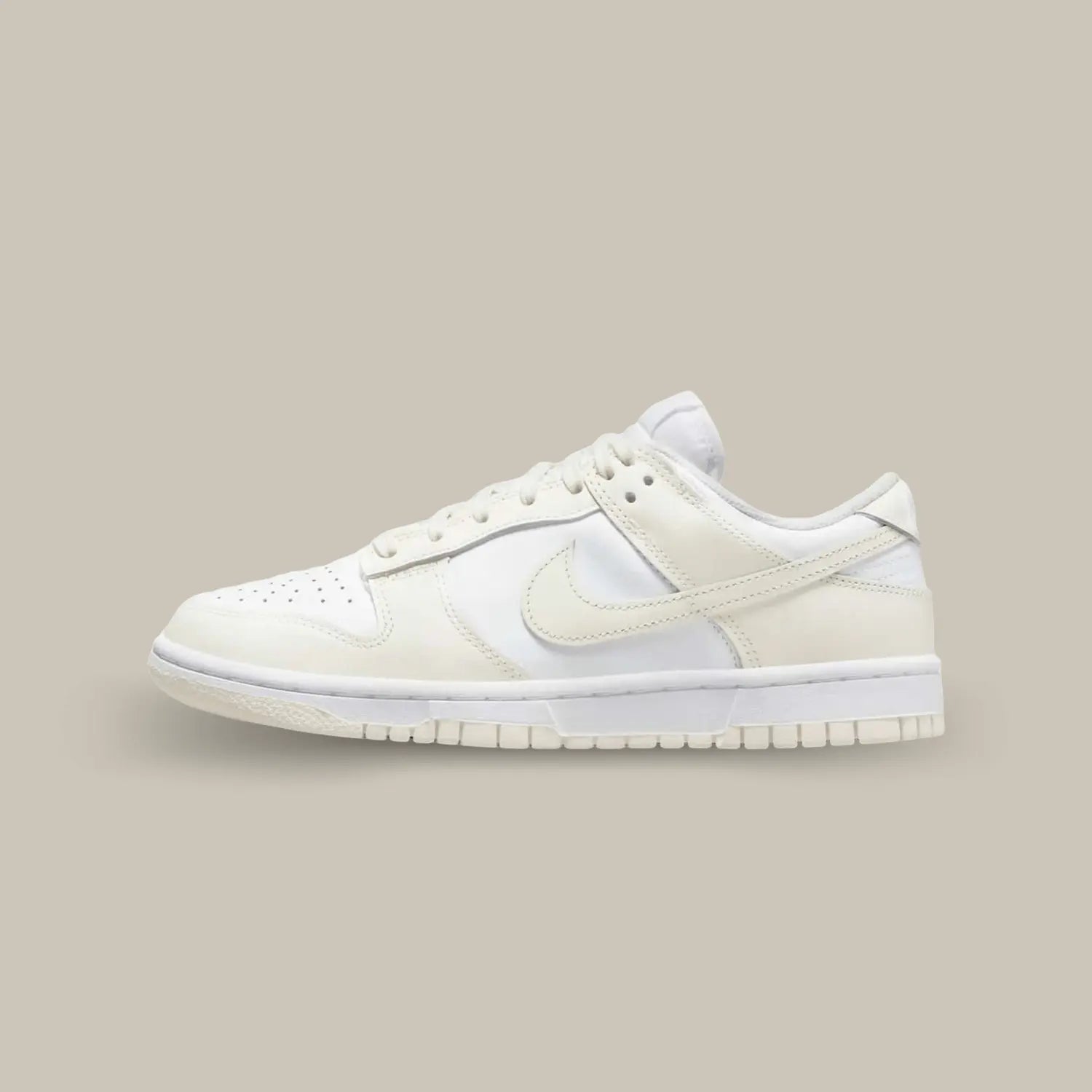 La Nike Dunk Low Coconut Milk de coté avec sa base en cuir blanc cassé, surélevée par des empiècements en cuir beige pastel.