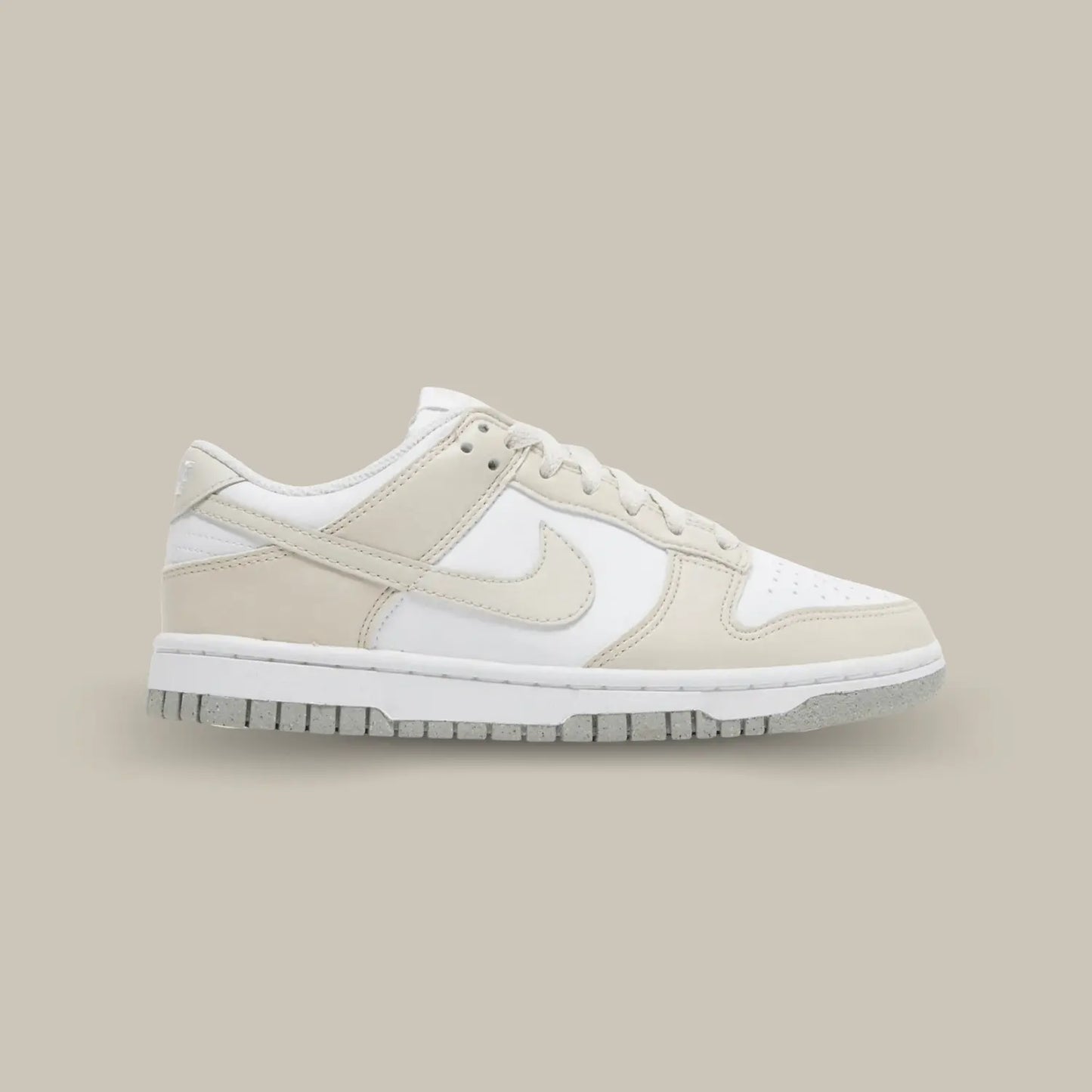 La Nike Dunk Low Next Nature White Light Orewood Brown de coté avec sa base en cuir blanc recyclé avec des empiècements en cuir crème. On retrouve le swoosh en cuir crème ainsi qu’une semelle grise qui vient compléter cette sublime Dunk.