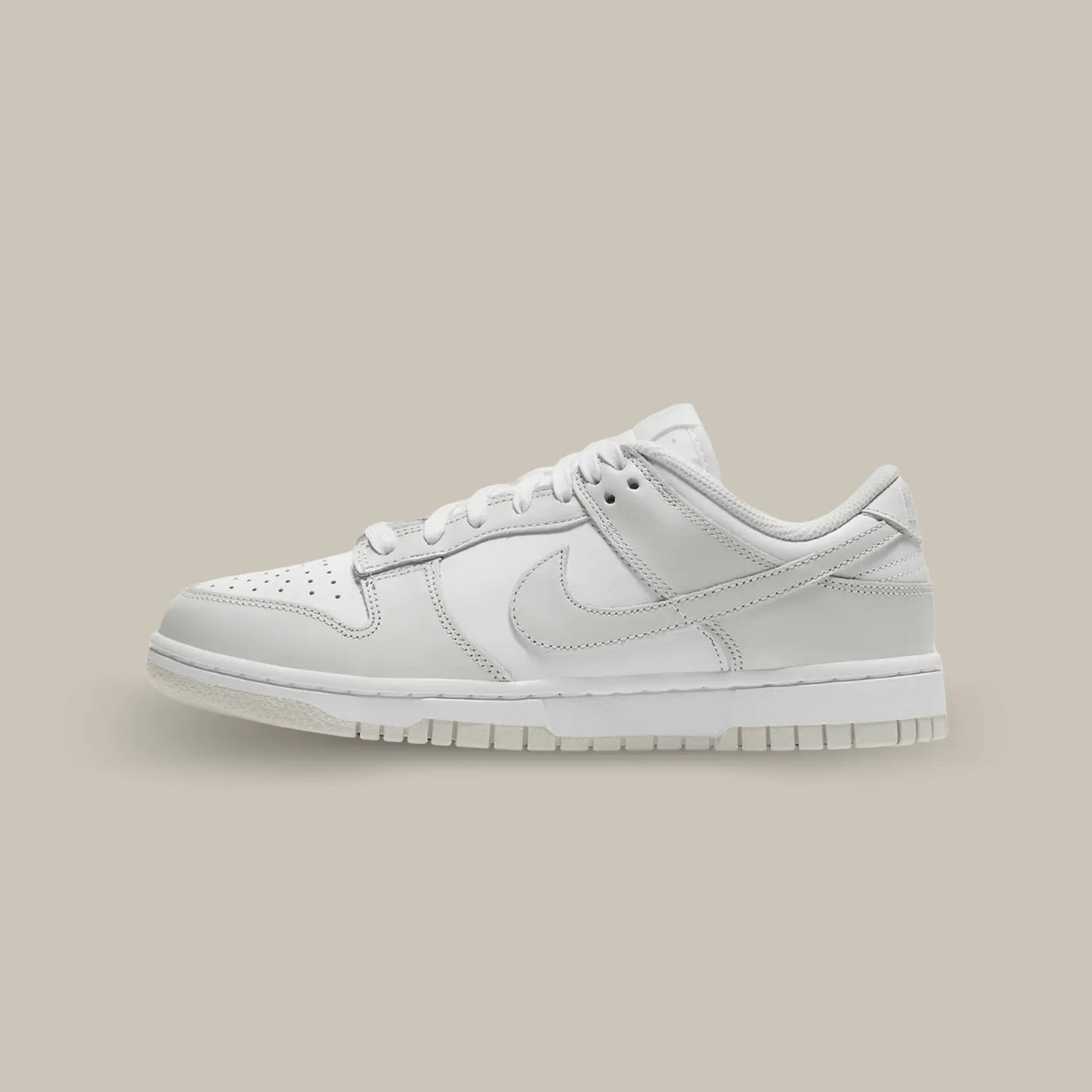 La Nike Dunk Low Photon Dust de coté avec sa base de cuir blanc pourvue d’empiècements en cuir gris.