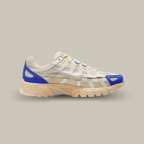 La Nike P-6000 Athletic Department Coconut Milk Medium Blue vue de côté avec sa base en mesh sail et ses superpositions en cuir blanc. Des touches de couleurs bleu se trouvent au niveau du talon et de l'avant de la paire.