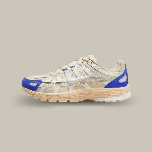 La Nike P-6000 Athletic Department Coconut Milk Medium Blue vue de côté avec sa base en mesh sail et ses superpositions en cuir blanc. Des touches de couleurs bleu se trouvent au niveau du talon et de l'avant de la paire.