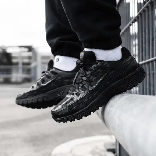 La Nike P-6000 Premium Triple Black portée avec un jogging noir.