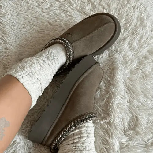 La UGG Tazz Slipper Hickory portée avec des chaussettes épaisses blanches.